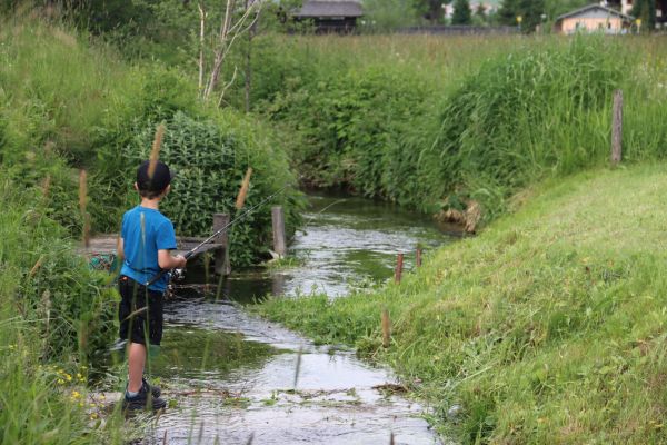 Kleiner Junge am Bach fischend.